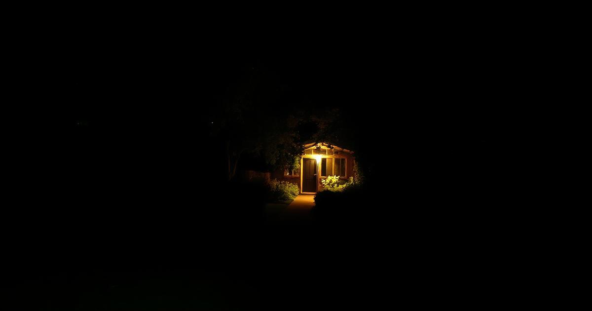 Quiet Hastings garden late at night with a single low warm light left on beside a path, the rest in darkness